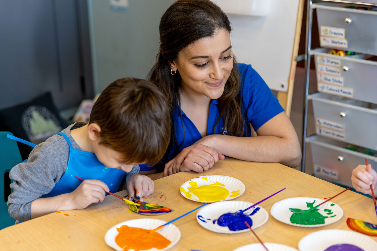 A teacher at a table with children painting