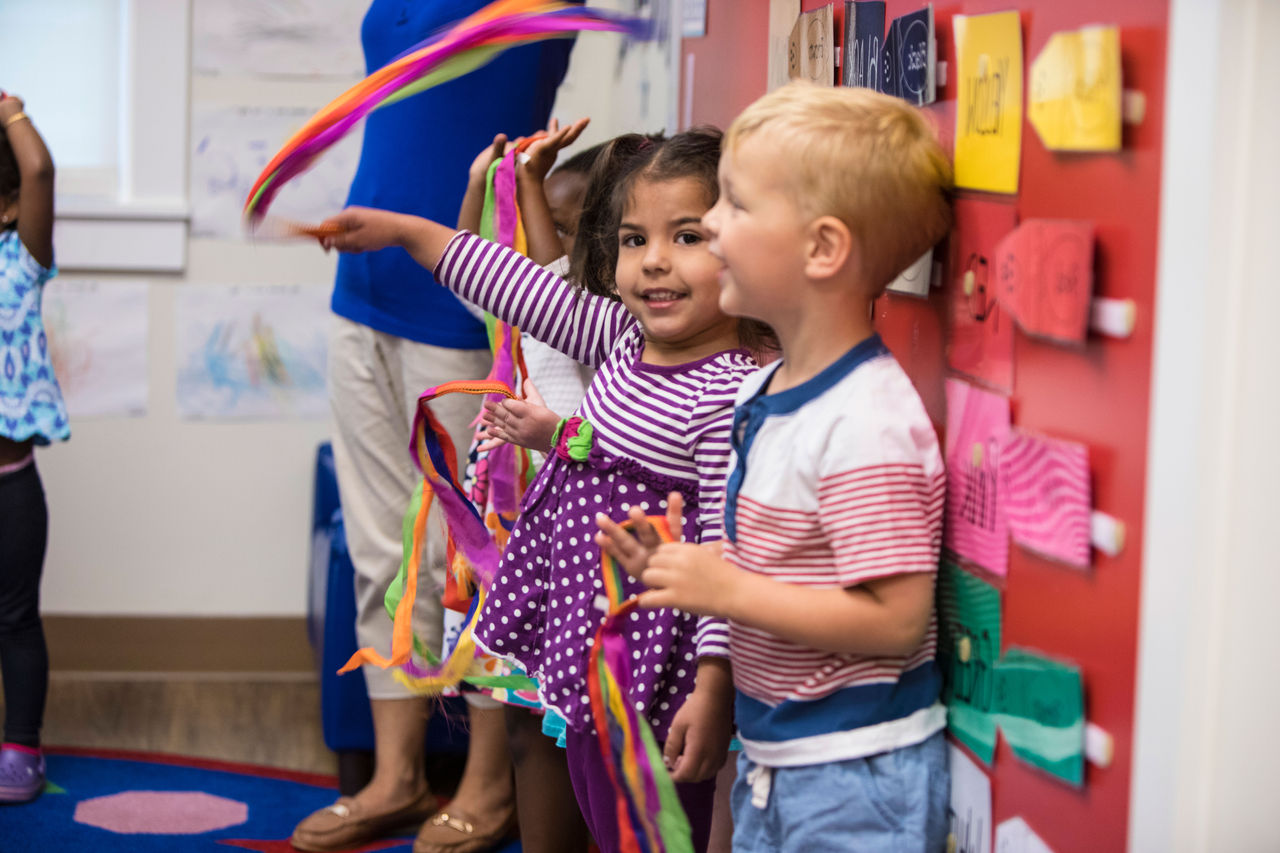 Kindergarten child waving ribbons with classmates