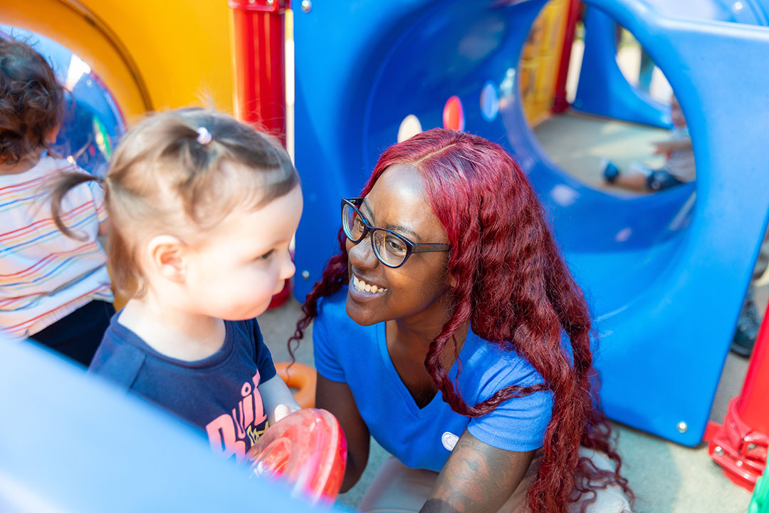 Teacher smiling at child on preschool playground