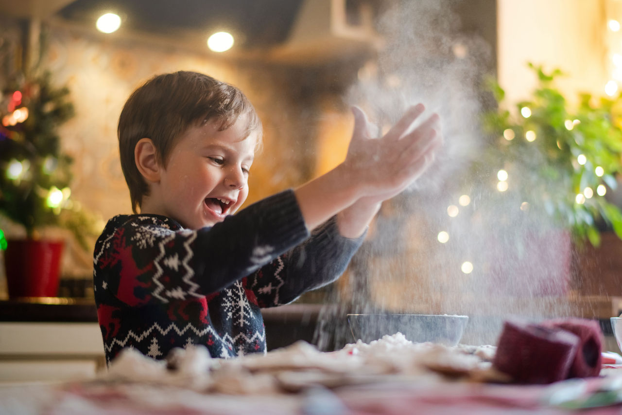 Child in kitchen baking throwing flour into the air