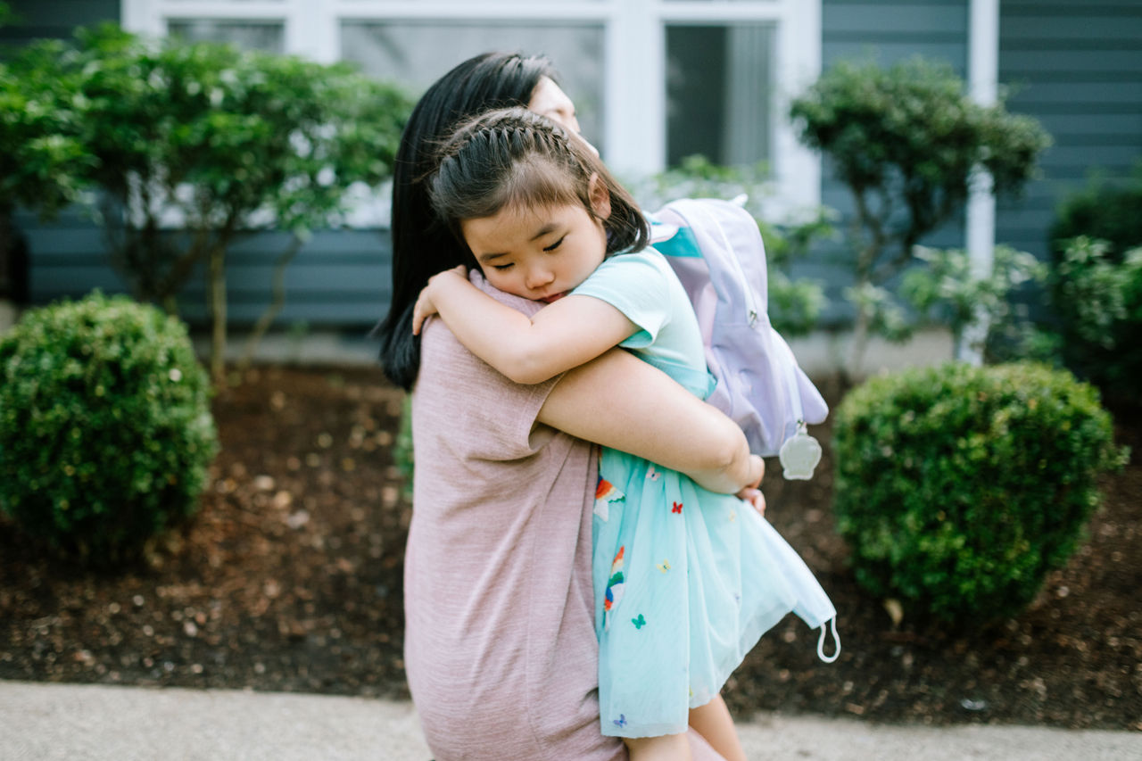 Little girl hugging her mom before going into school