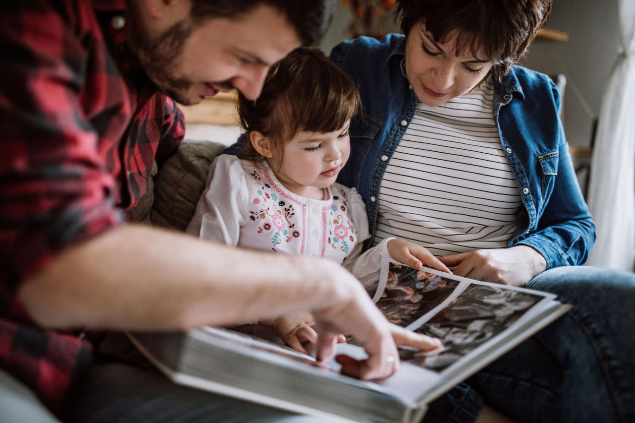 A mother and father looking at a photo book with their daughter