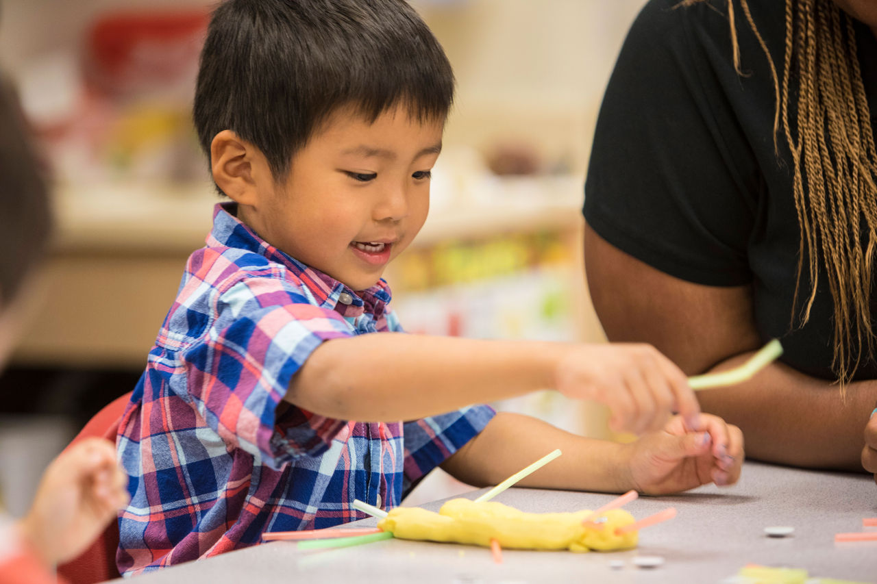 Child works on craft project at table in preschool classroom