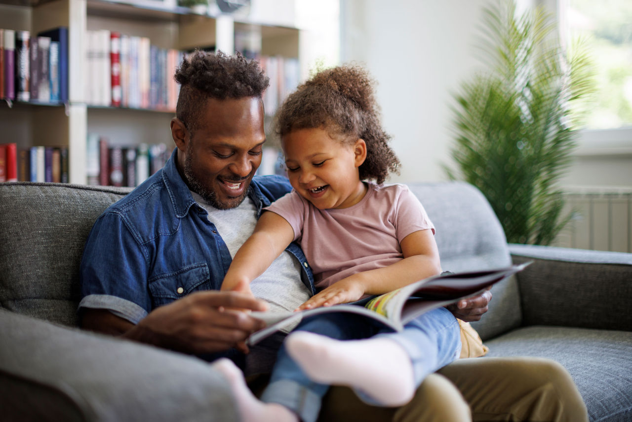 Dad and daughter reading a book together on a couch