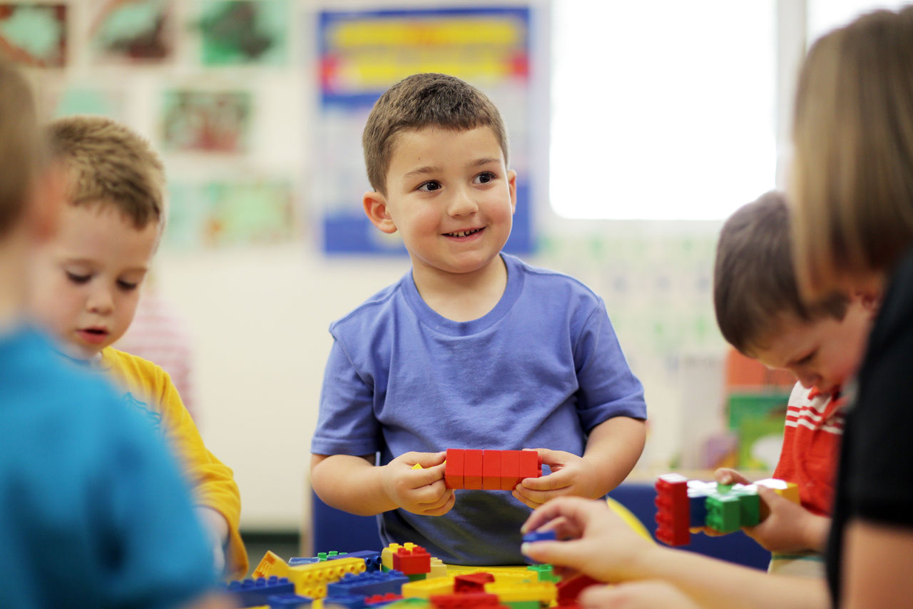 Boys and teacher at a table playing with stackable block toys