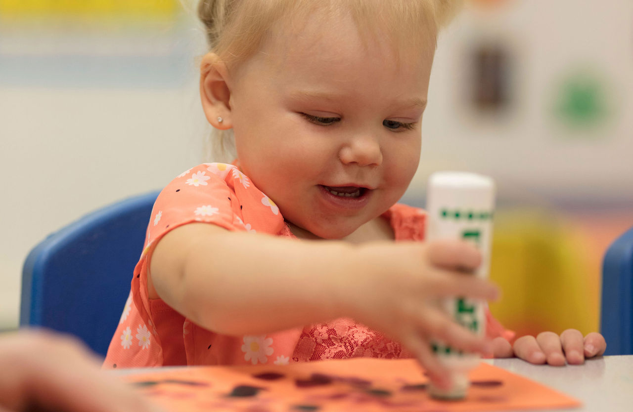Small girl sitting at a preschool table stamping on paper with a bingo blotter