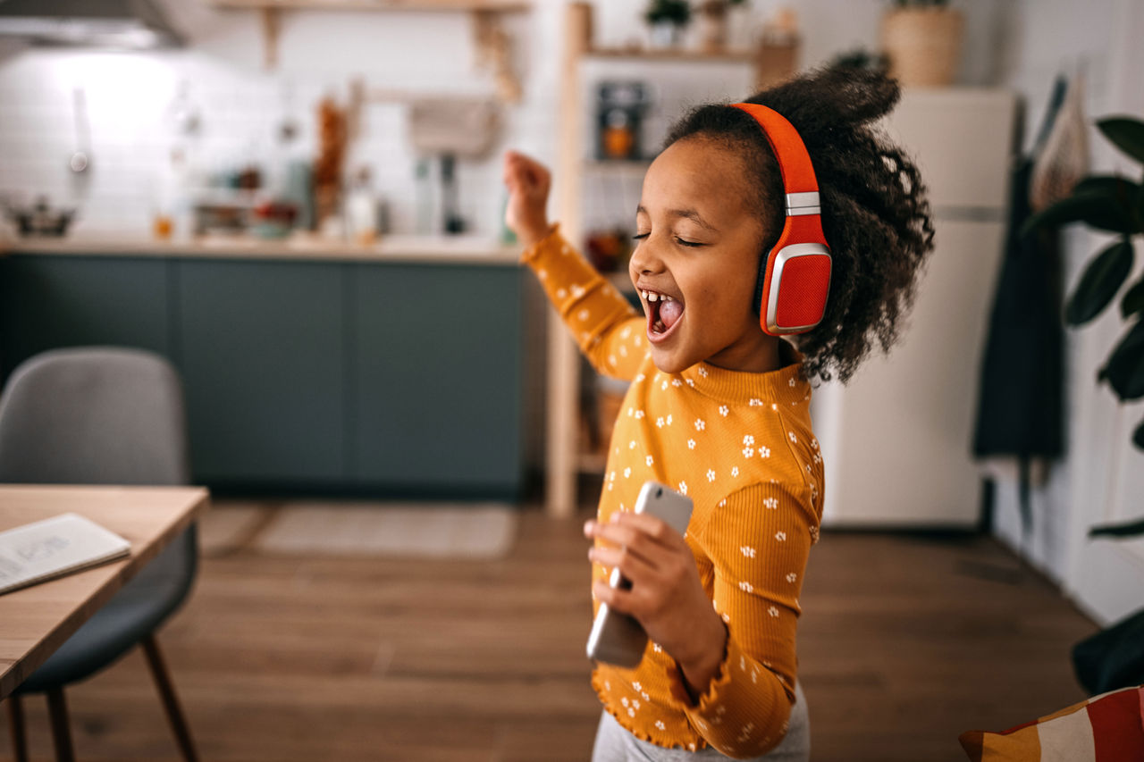 A young girl wearing headphones, singing and dancing