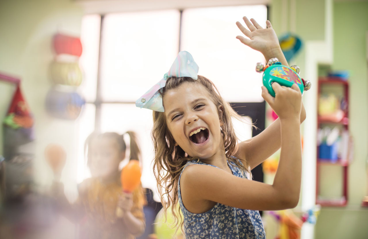 Kindergarten student dancing with an instrument in classroom