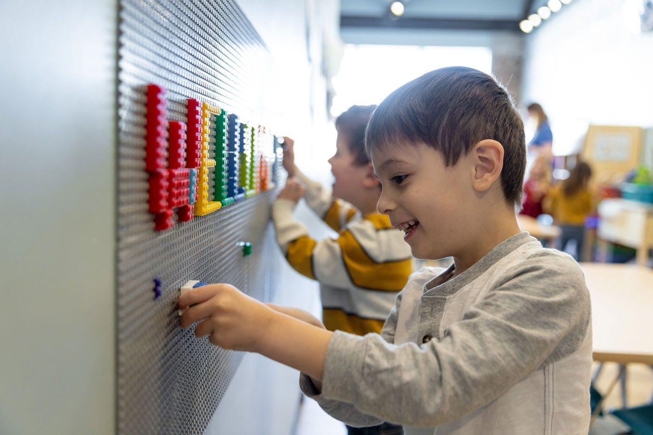 Kindergarten students creating art on classroom wall