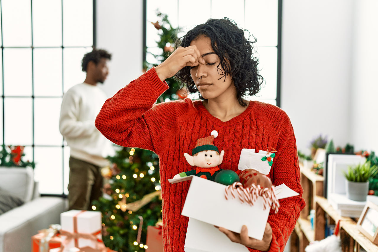woman looking stressed out while holding holiday items