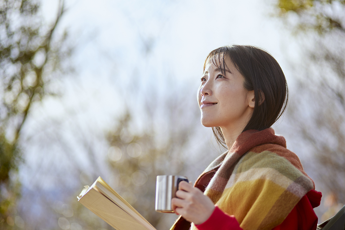 Parent enjoying a quiet moment outdoors with a book and coffee, highlighting the importance of self-care for preschool parents and caregivers.