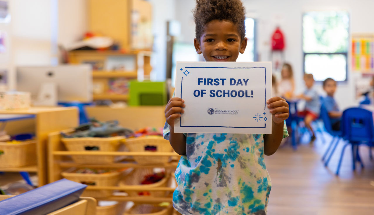 boy in classroom holding first day of school sign