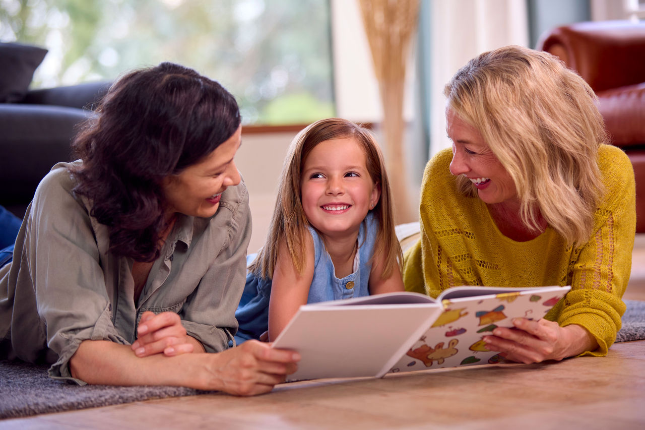 Mothers reading a book on the floor with their child