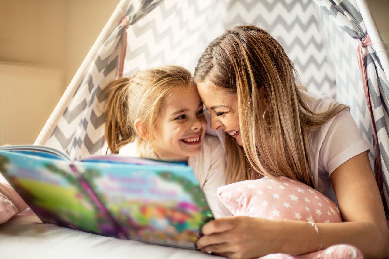 Mother and child reading a book in a tent