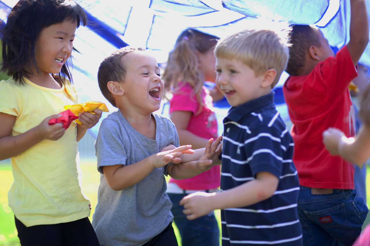 Children under a play parachute smiling and laughing