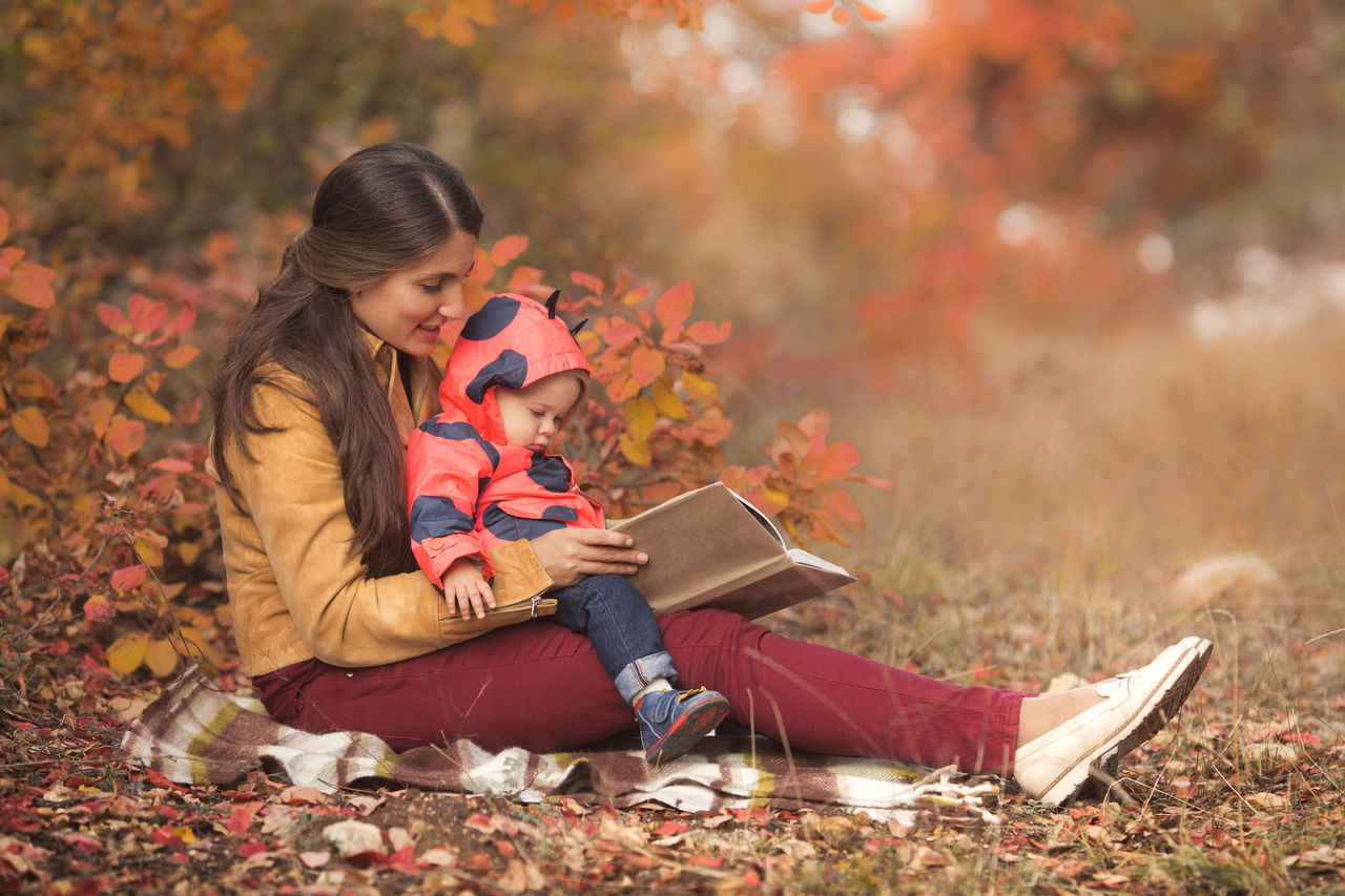 mom and baby reading on a blanket in the leaves