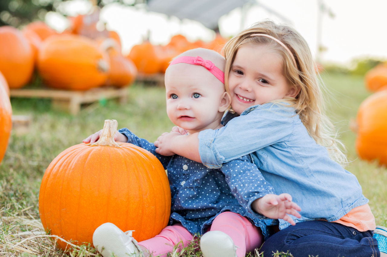 Young girls smiling and hugging in a pumpkin patch