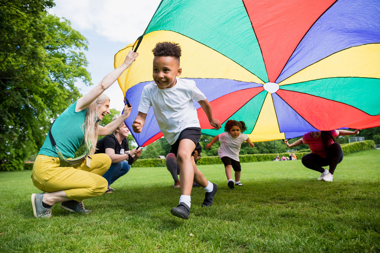 smiling children playing under a play parachute