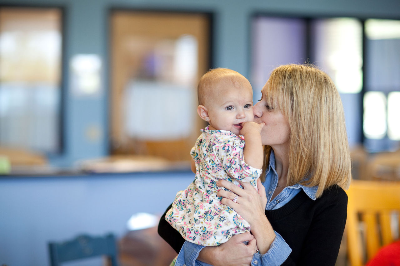 Mother kissing her infant in a daycare classroom