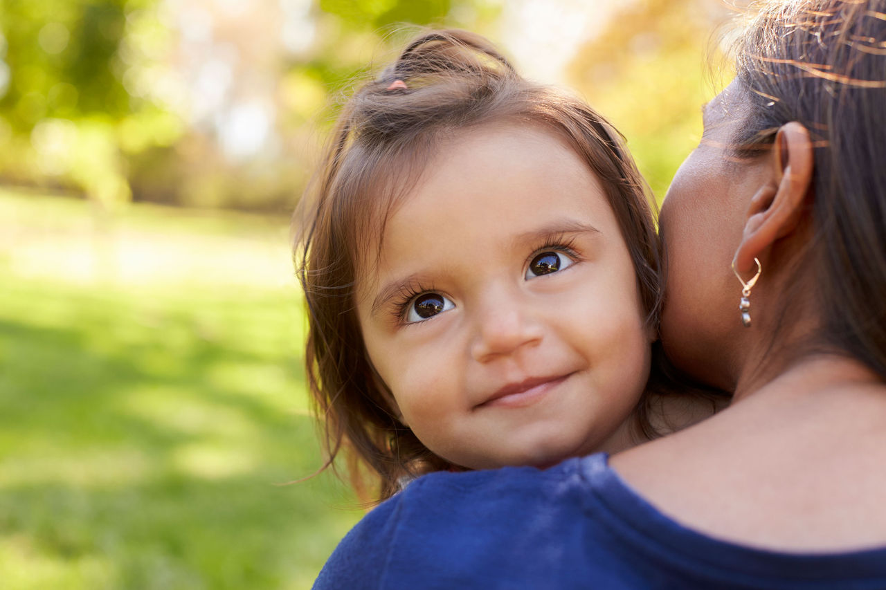 child looking over a mother's shoulder while being held