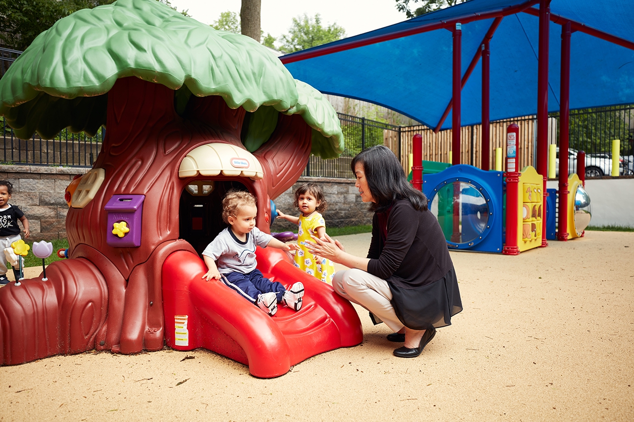 A teacher plays with a toddler on the infant/toddler playground.
