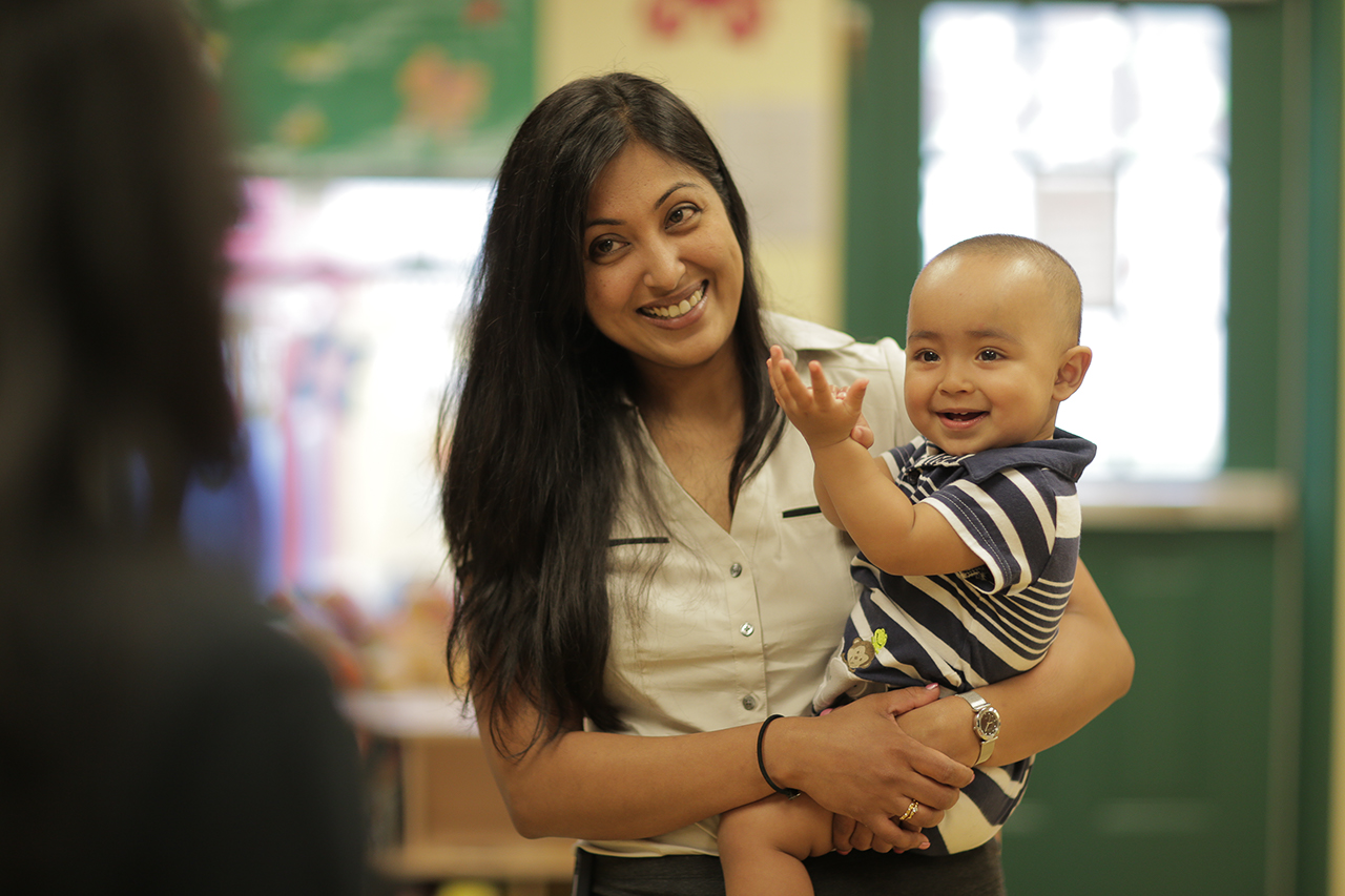 A smiling mother holds her infant in a Goddard classroom.