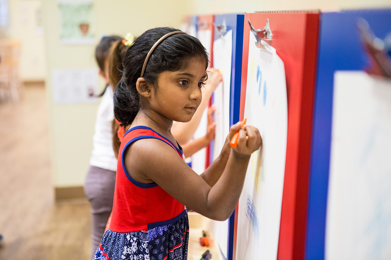 A girl draws at an easel.