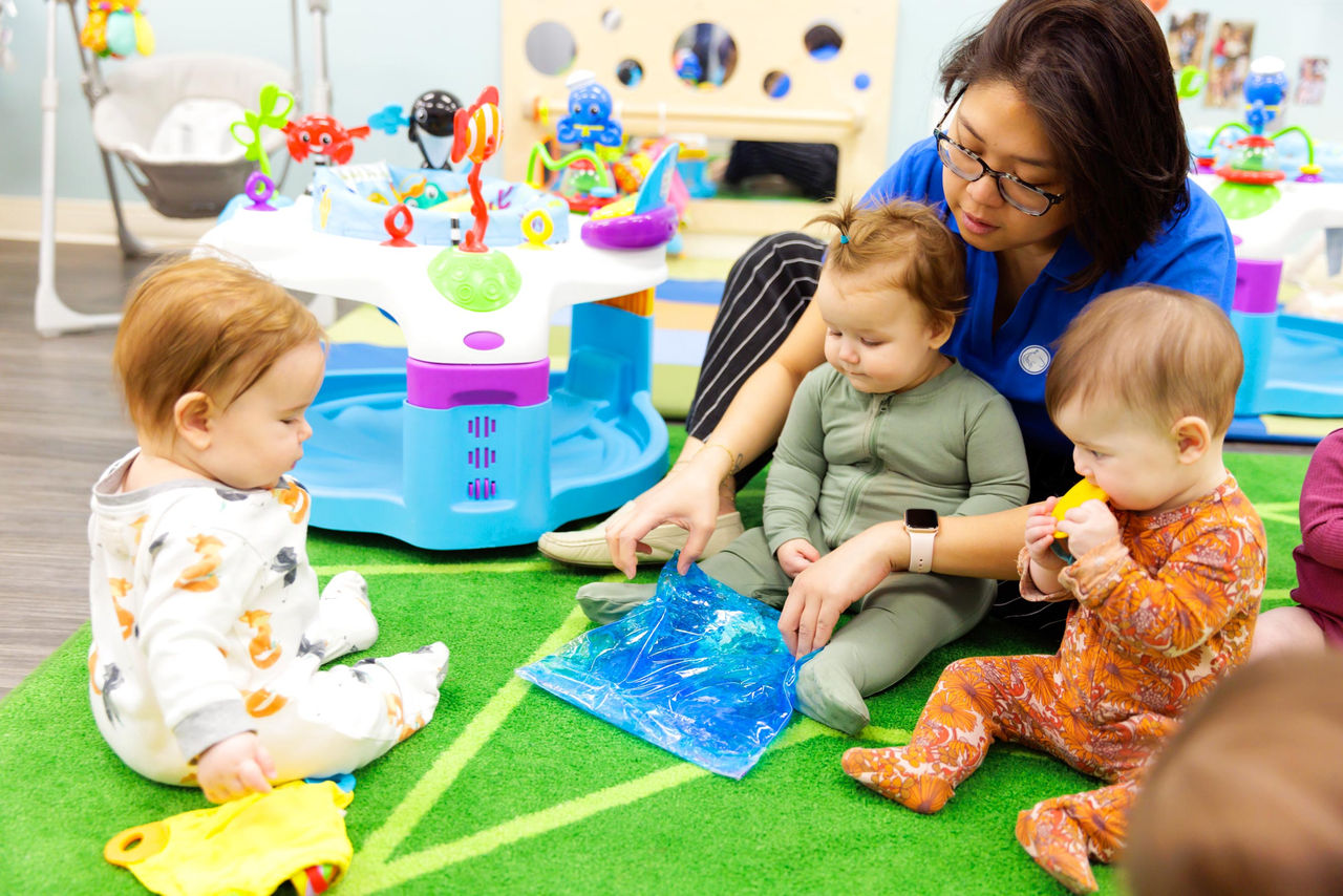 A teacher showing toddlers a colorful piece of paper